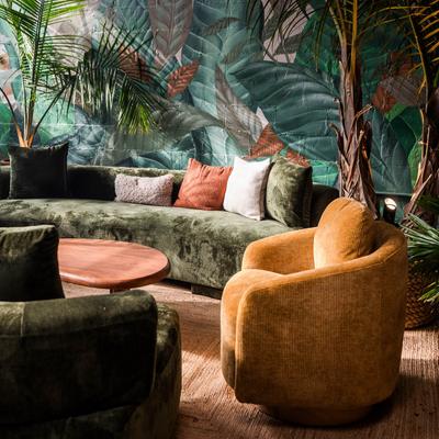 Interior, seating featuring green sofas, coffee table, yellow armchair, plant wall mural.