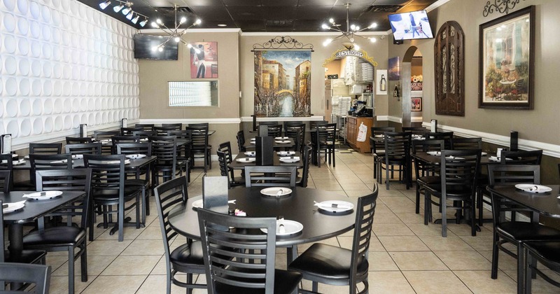 Interior seating area with black tables, chairs and set plates