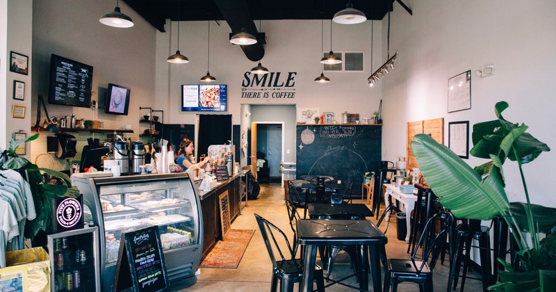 Interior of a coffee shop with seating, a pastry display and a chalkboard