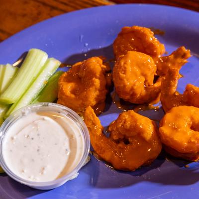 Buffalo Shrimp served with celery sticks and a dipping sauce.