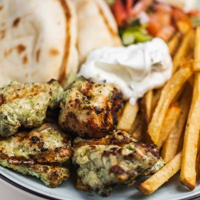 Grilled chicken with fries, tzatziki, pita bread, and salad.