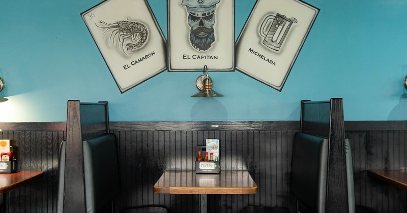 Booth with cards on wall depicting a prawn, a captain and a beer mug