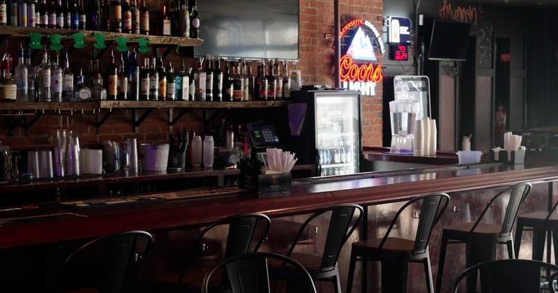 Bar, drink rack, stools, light sign on the brick wall behind