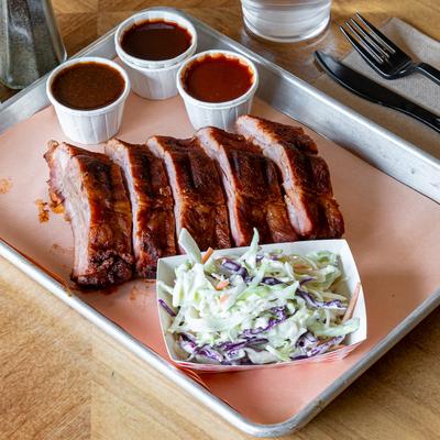 Baby Back Ribs with BBQ sauces and coleslaw on the side.