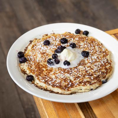 Blueberry pancakes topped with whipped butter, powdered sugar, and blueberries.