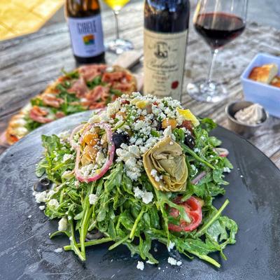 Mediterranean Salad on a table with Margherita Pizza and wine.