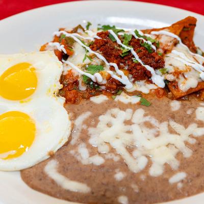 Chips, chorizo, onion, tomato, cilantro, eggs, cheese, sour cream, and refried beans.