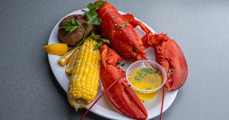 Steamed lobster with baked potato, corn on the cob, drawn butter, and lemon