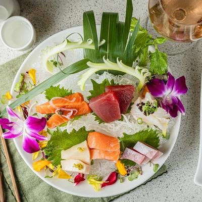 Sashimi sampler served with sake and wine, top view.