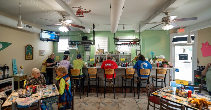 Bar area featuring ceiling fans, coastal decor and guests seated at the counter