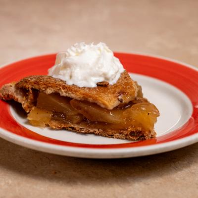A piece of apple pie with whipped cream.