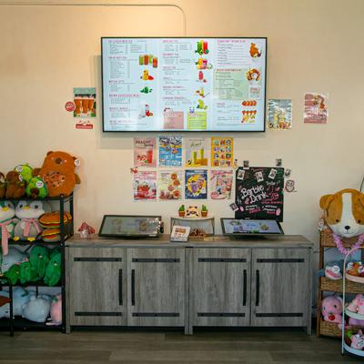 Interior with a digital menu board, plushies, and posters.