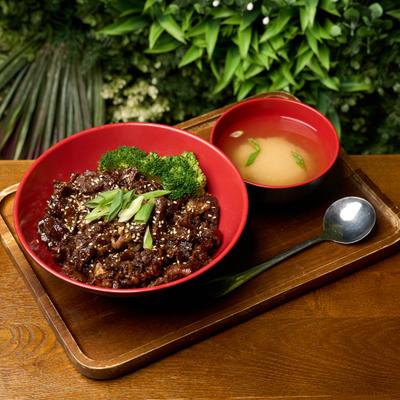 Bowl of glazed beef with broccoli and sesame seeds served with miso soup.