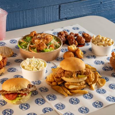 Fried chicken sandwiches, wings, fries, and sides on a table.