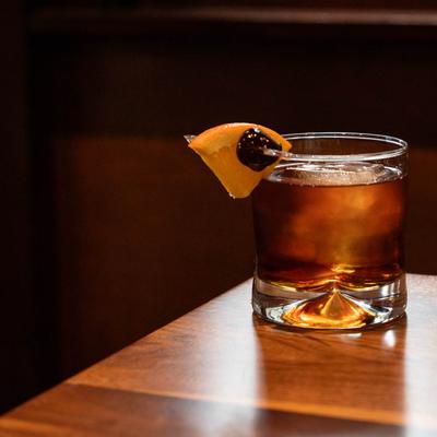 A glass of Old Fashioned placed on the corner of a table.