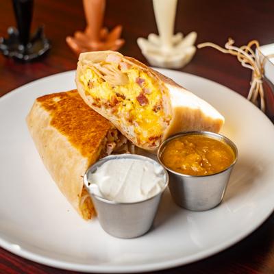 Breakfast burrito served with salsa and sour cream.