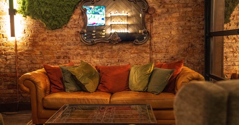 Interior, lounge area, three seater sofa with pillows, vintage brick wall, coffee table