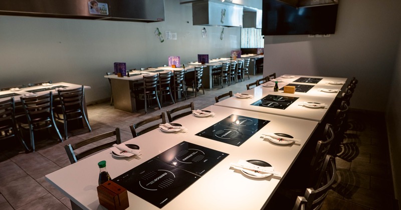 Dining area with tables featuring induction cooktops, set for group dining