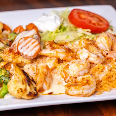 Grilled shrimp on a bed of rice topped with queso dip, sauteed vegetables, lettuce, and sour cream.