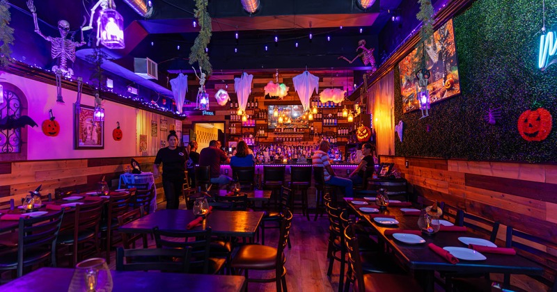 Interior, seating area featuring set tables and a bar with seated guests