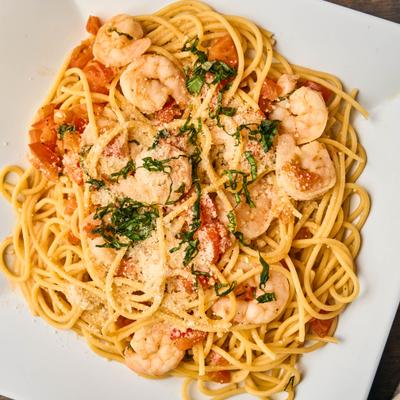 Shrimp Fra Diavolo served over spaghetti, topped with grated cheese and herbs.