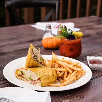 Smoked Turkey Wrap served with fries and a cocktail.