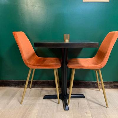 Restaurant seating with a small table and two orange chairs against a green wall.