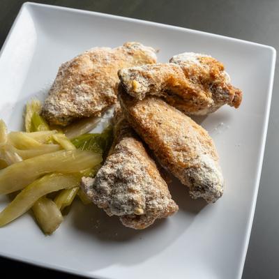 Smoked wings with salt and vinegar beside pickled vegetables.