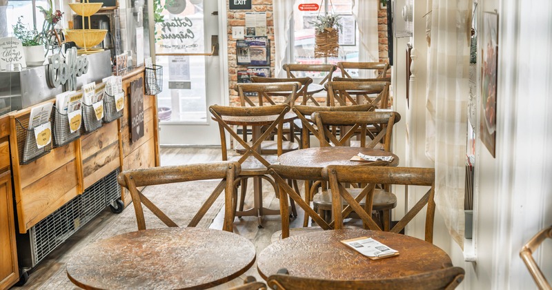 A cozy interior with wooden tables and chairs, rustic decor and a counter with coffee-related items.