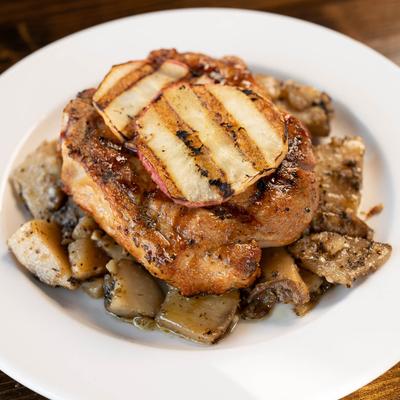 Pork chop topped with grilled apple slices and served over roasted potatoes.