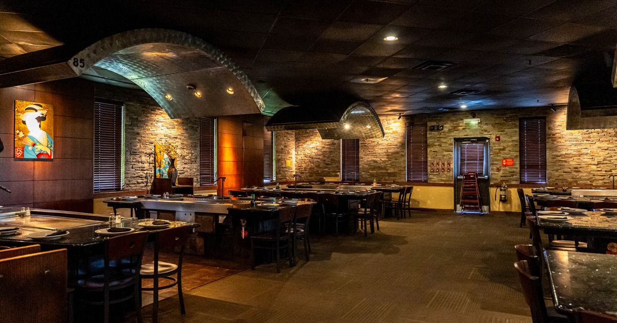 Interior of a restaurant featuring modern decor, cooking tables, colorful artwork