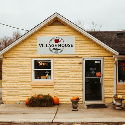 Village House Coffee shop exterior with signage and pumpkin decor.