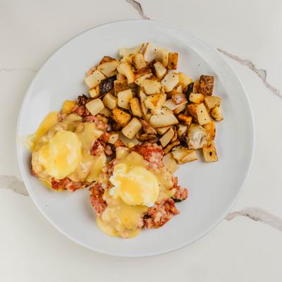 Eggs Benedict with corned beef and hollandaise, served with home fries.