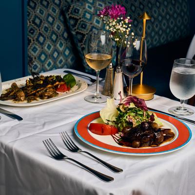 A restaurant table with wine, salad, and colorful decor.