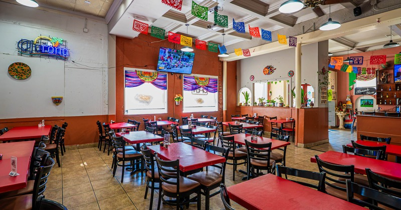 Restaurant dining room with red tables and colorful papel picado decorations