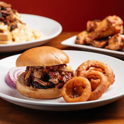 Burger, with brisket, BBQ sauce, aged cheddar, onions, and a side of onion rings.