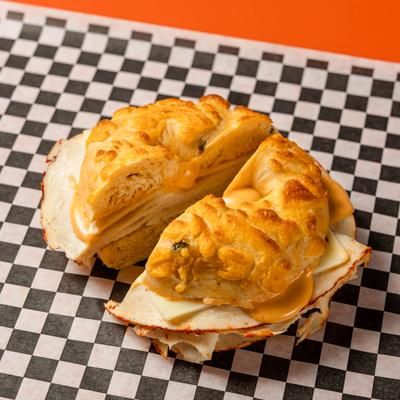 Buffalo chicken bagel sandwich topped with cheese and buffalo sauce.