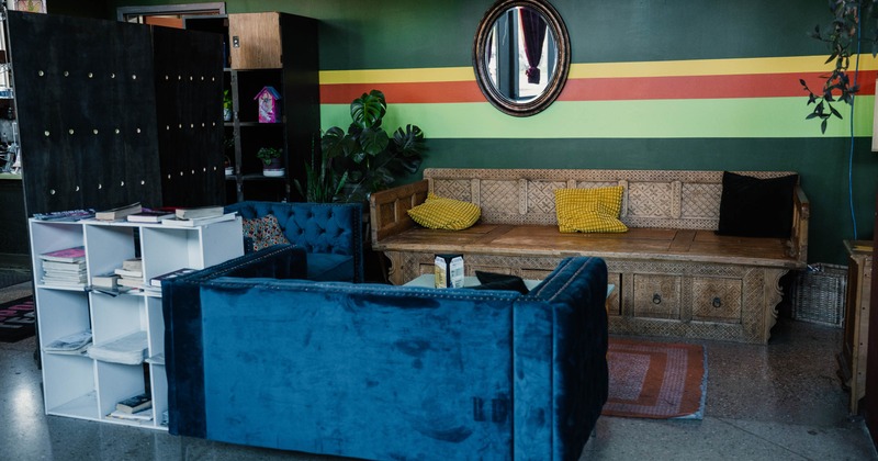 A wooden bench with yellow pillows and blue velvet sofa