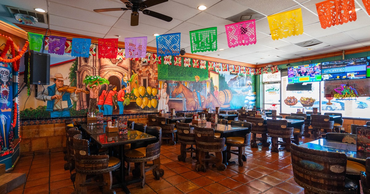 Interior of a restaurant with vibrant murals and papel picado banners