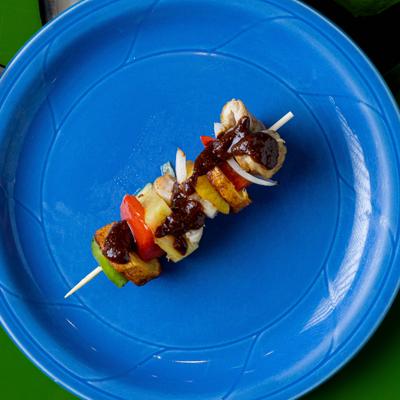 Chicken skewer with grilled vegetables and sauce on a blue plate.