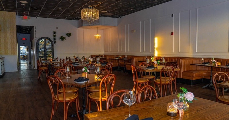 Elegant restaurant interior with wooden tables, chairs, and booth seating under chandeliers