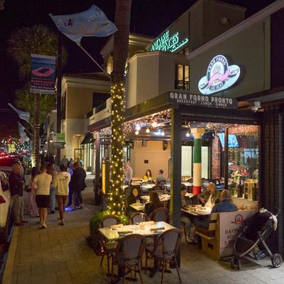 Exterior, outdoor seating with decorative string lighting, entrance and signage.