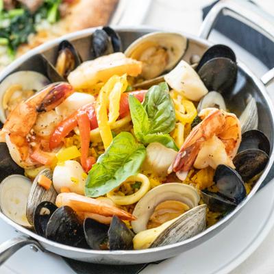 Seafood paella with shrimp, mussels, shrimp, and basil garnish.