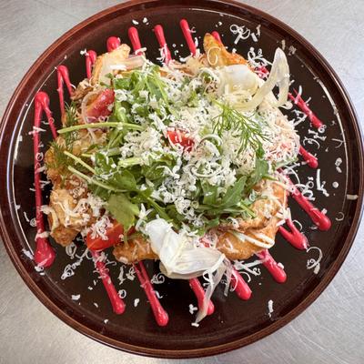 Dish topped with shredded cheese, fresh arugula and cherry tomatoes.