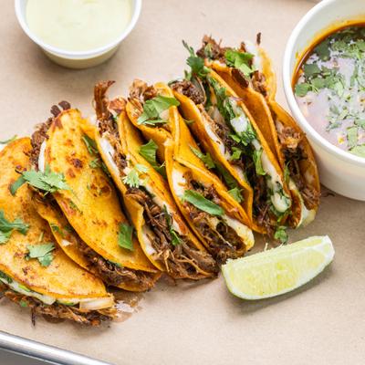Smoked birria tacos paired with broth and lime.