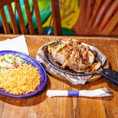 Potato Fajita served in a skillet alongside a separate plate with sides of rice and salad.