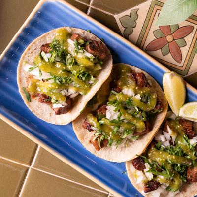 Steak tacos, with onion, cilantro, lime, and green salsa.