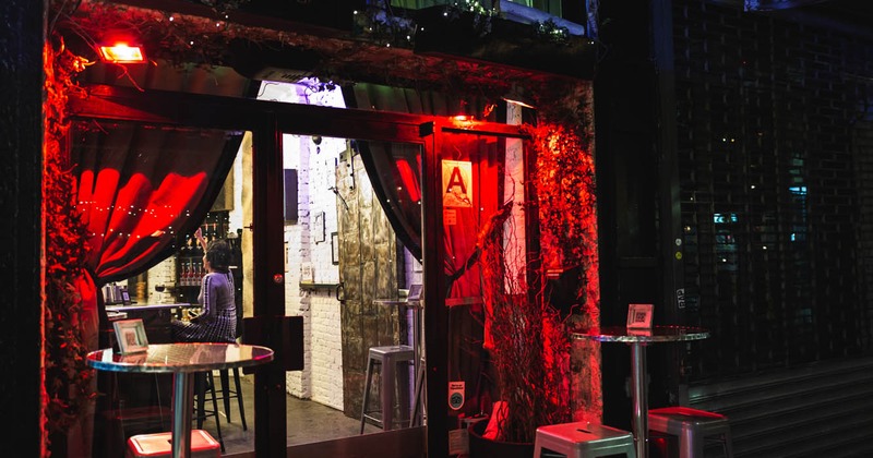 night photo of the glass door entrance lit with red lights and covered with plush curtains