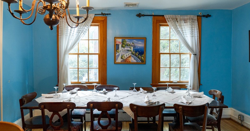 Interior, set table by curtained windows, blue walls with an artwork