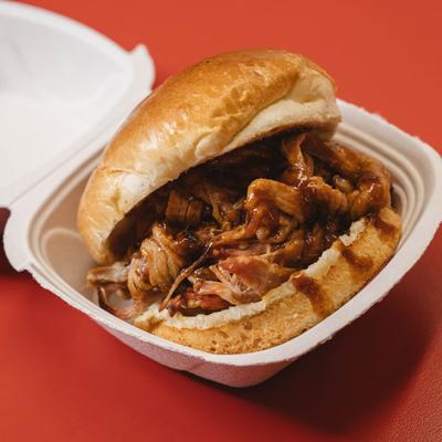 A pulled pork sandwich in a take-out container.